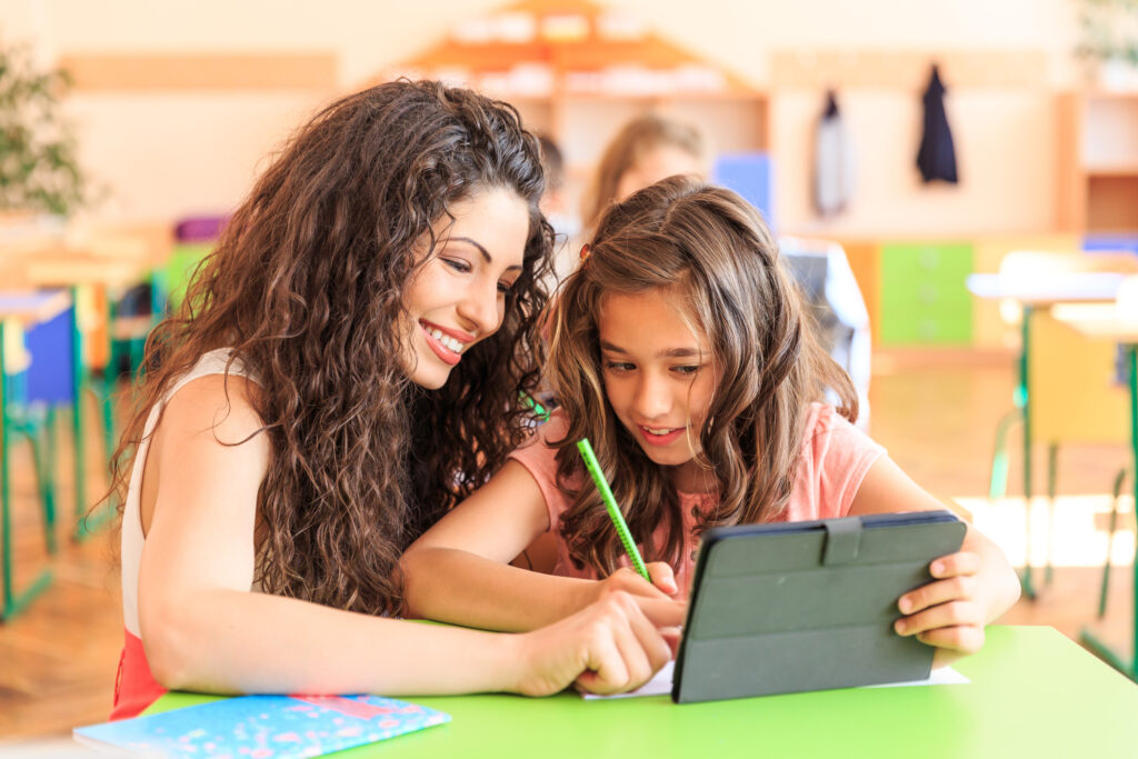 teacher helping student on tablet