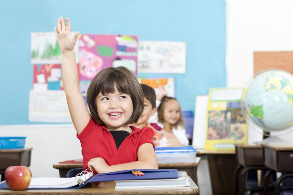 young girl raising hand in class