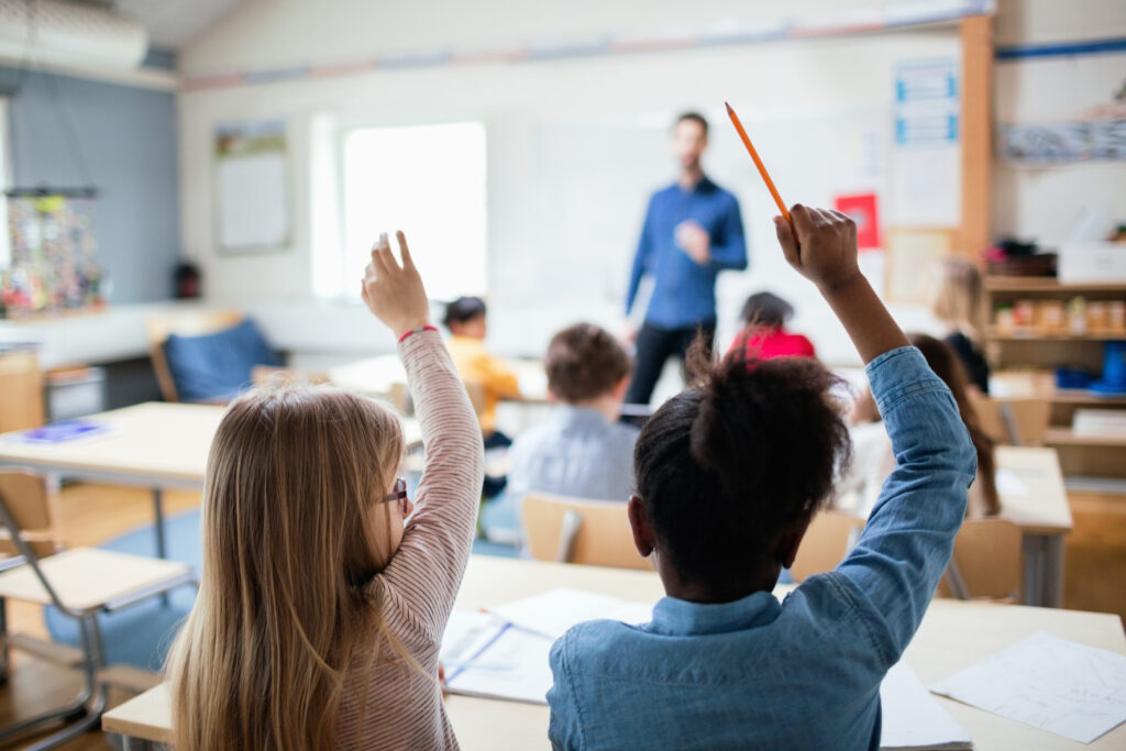 kids raising hands in classroom