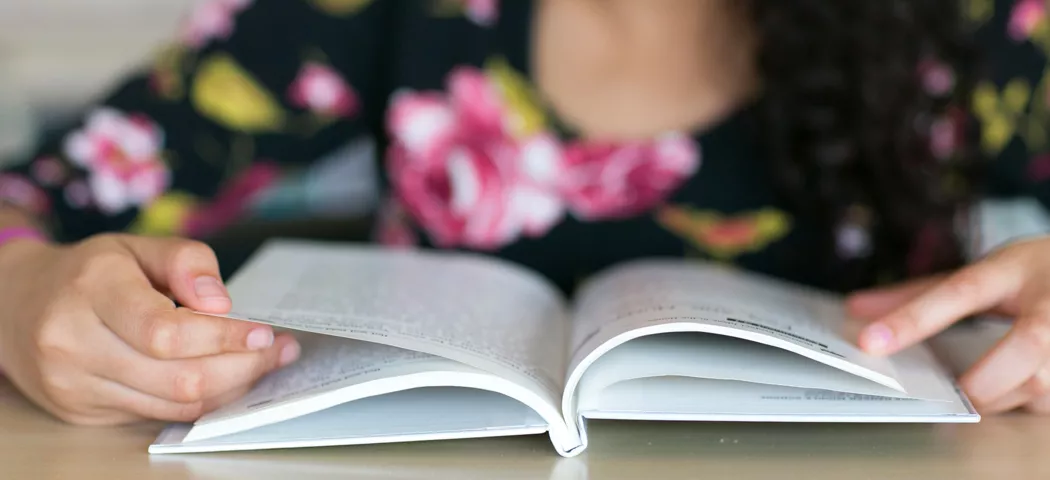 girl opening book on desk