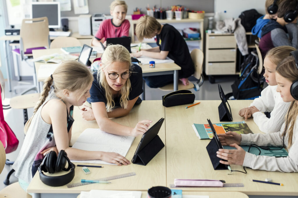 teacher helping students on tablet