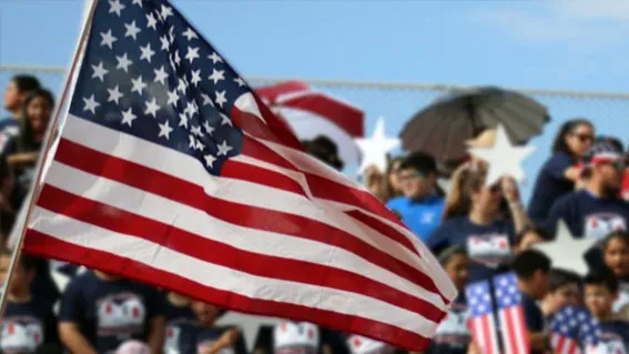 American flag waving in front of a proud crowd of Americans