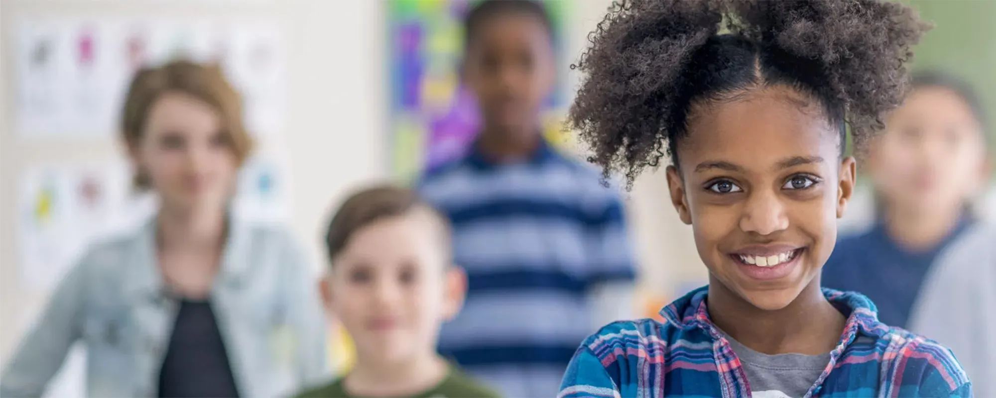 Smiling girl in front of a group of her peers at school