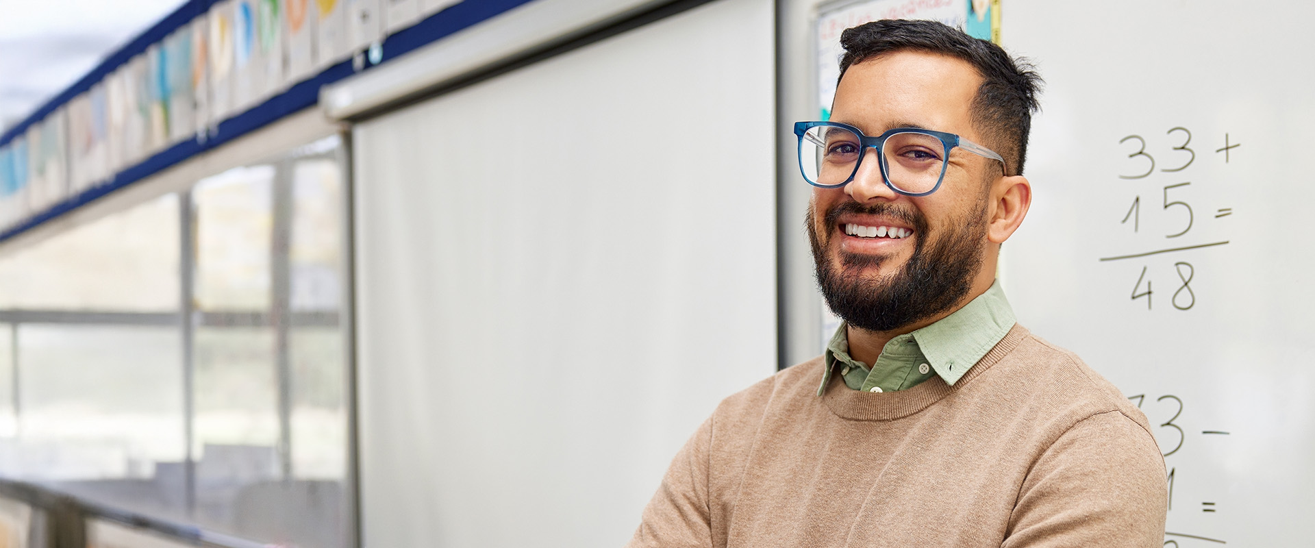 a male math teacher with fractions on a white board smiling