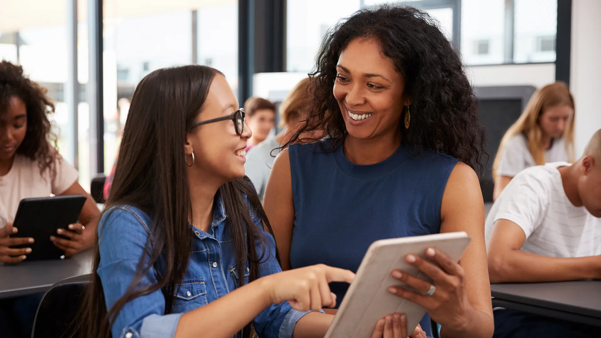 a teacher with a student holding a tablet